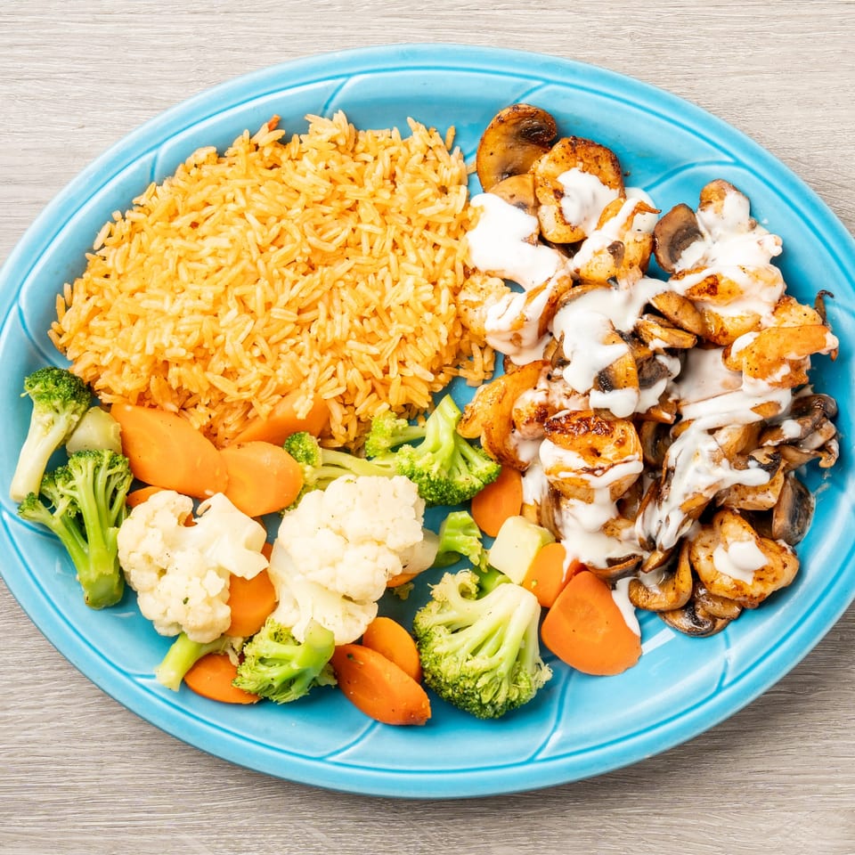 Mis Arcos' shrimp and mushrooms with white sauce, rice, and steamed vegetables on a blue plate.