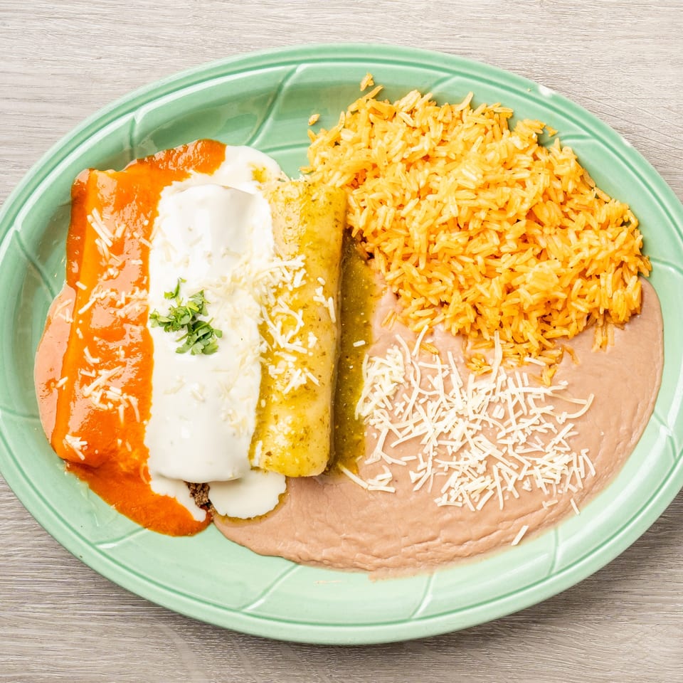 Mis Arcos enchiladas with red and green sauce, rice, and refried beans on a green plate.