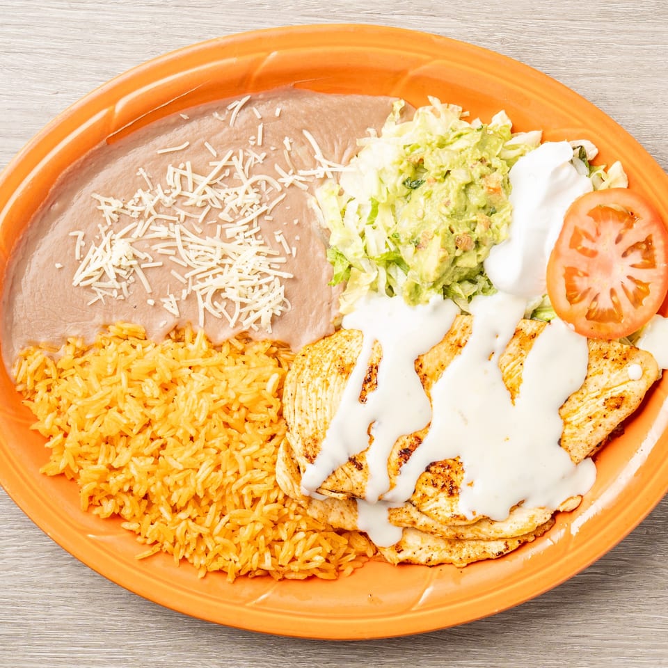 Mis Arcos Mexican Restaurant's chicken dish with rice, beans, guacamole, sour cream, and tomato.
